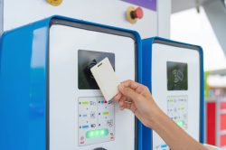 A hand tapping EV charging point card to reader machine. Unlock the station. Electric vehicles battery. Chargeable device or electronic.